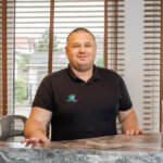 Mężczyzna w czarnej koszulce za ladą recepcji