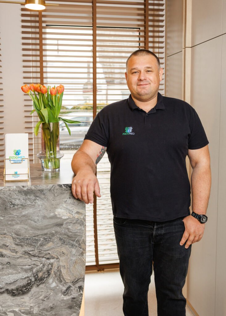 Mężczyzna w czarnej koszuli stoi obok stanowiska recepcji.